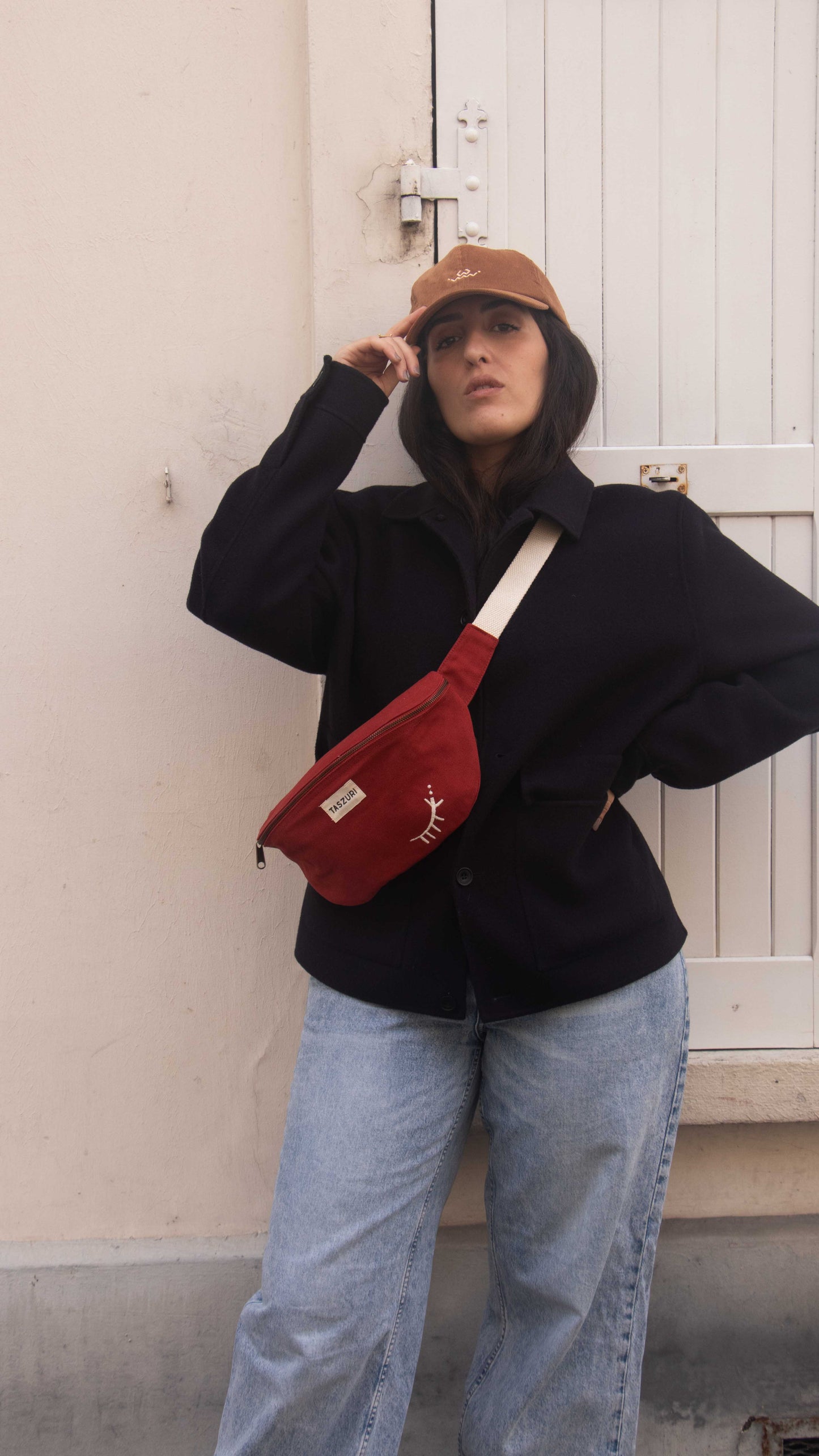 Sac banane azel rouge piment et casquette tara caramel  - vue portee de loin main sur casquette